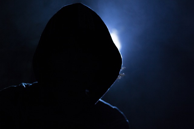 Image of hooded hacker in darkness used to represent hacking.